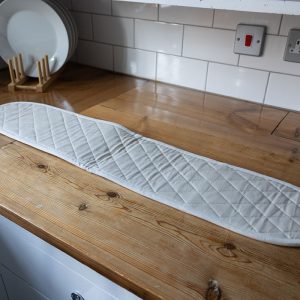 long white double oven mitt laid out on a kitchen countertop