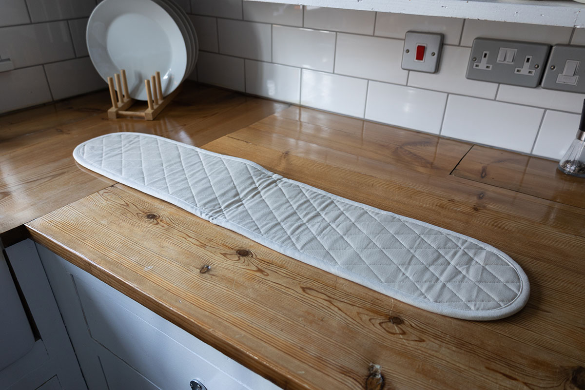 long white double oven mitt laid out on a kitchen countertop