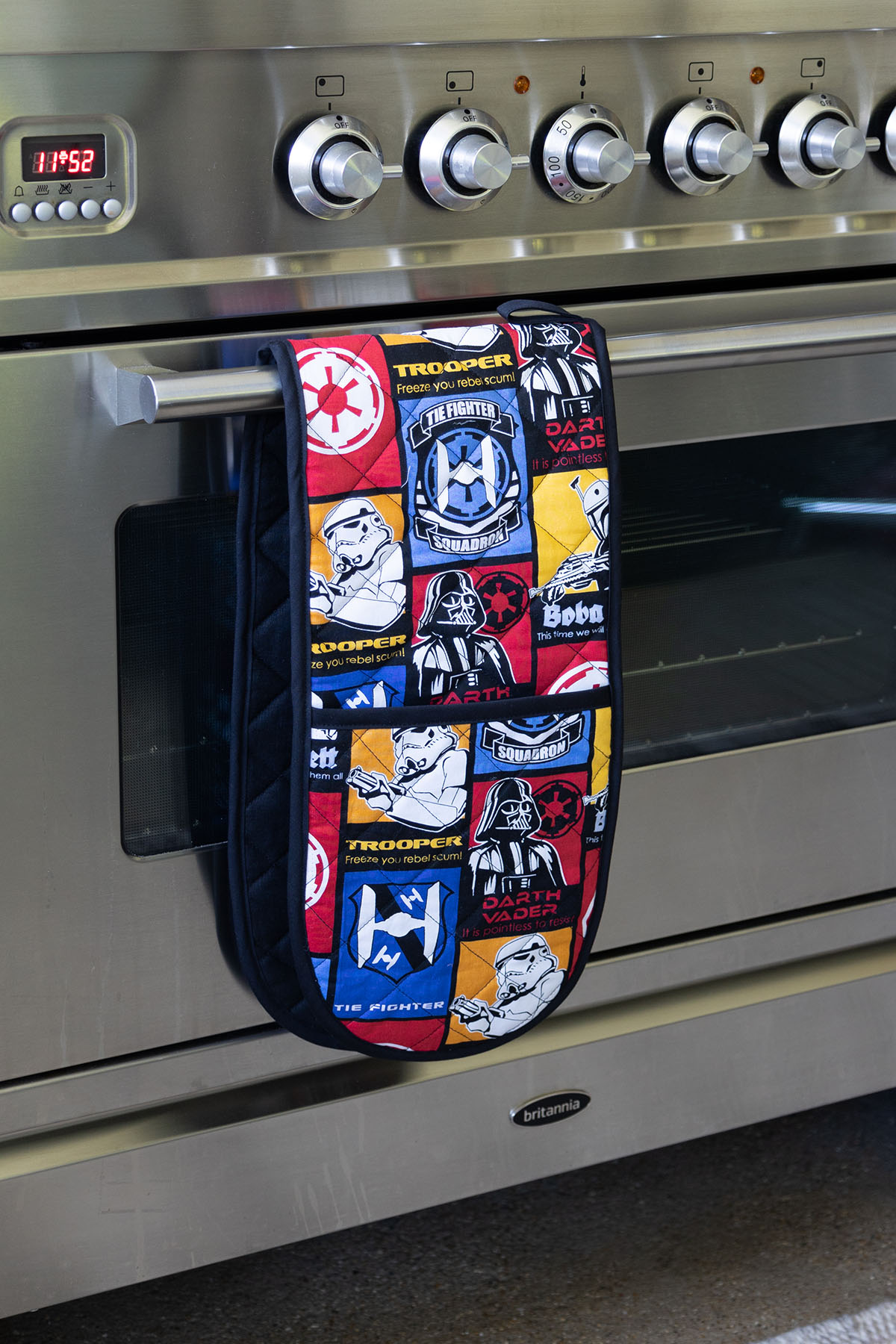 blue, red, yellow, Star Wars fabric made into a double oven mitt, hanging on a silver oven
